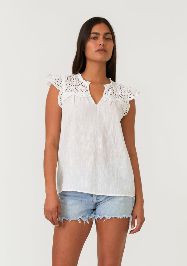 [Color: White] A front facing image of a brunette model wearing a white bohemian spring top with short cap sleeves, a split v neckline, and an eyelet lace yoke. 
