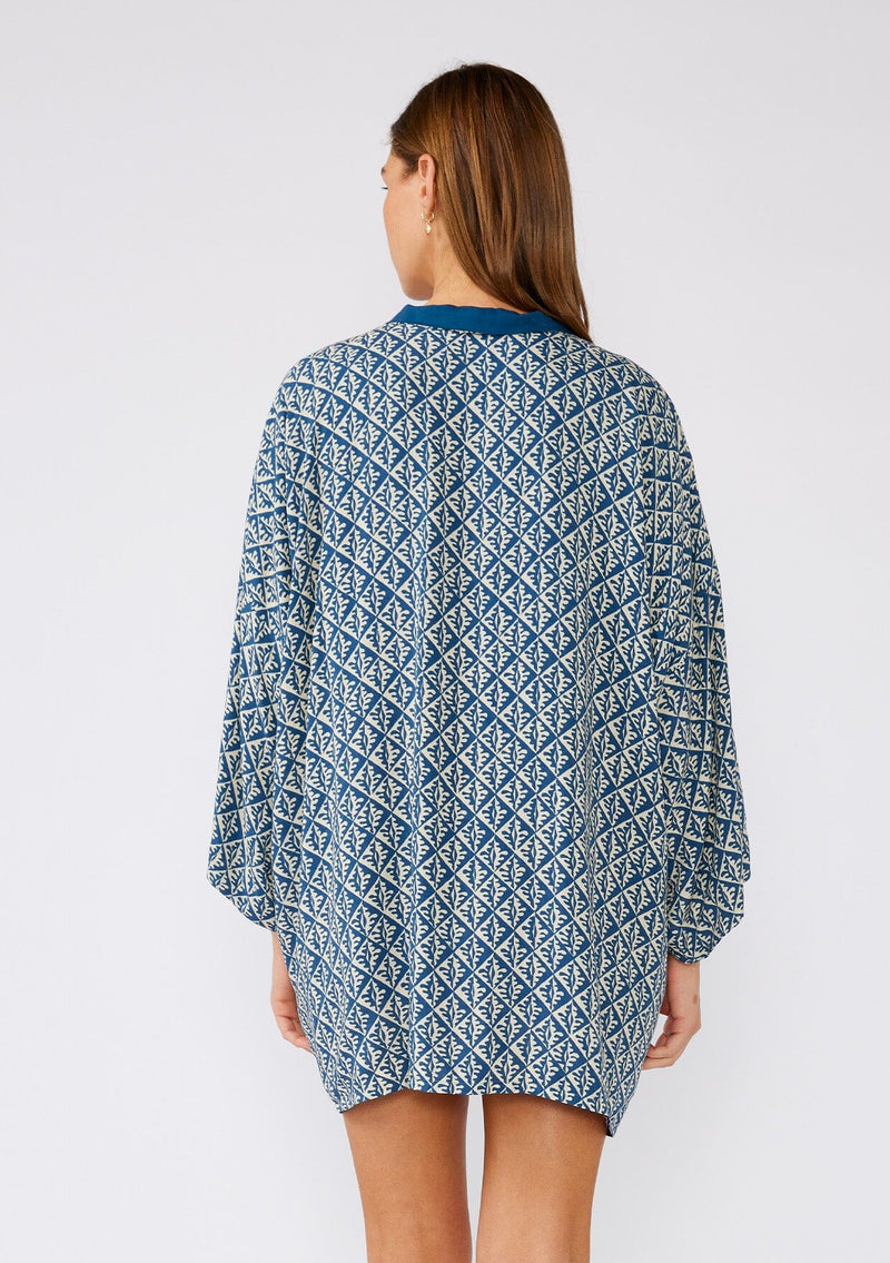 [Color: Indigo/Blue] A half body back facing image of a brunette model wearing a bohemian kimono in an indigo blue print. With three quarter length long sleeves, an open front, and a mid length. A reversible cover up for the beach or pool side. 