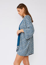 [Color: Indigo/Blue] A half body side facing image of a brunette model wearing a bohemian kimono in an indigo blue print. With three quarter length long sleeves, an open front, and a mid length. A reversible cover up for the beach or pool side. 