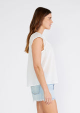 [Color: White] A side facing image of a brunette model wearing a white bohemian top crafted from lightweight cotton gauze. With short cap sleeves, a split v neckline, gathered details at the yoke, and a raw edge hem. 
