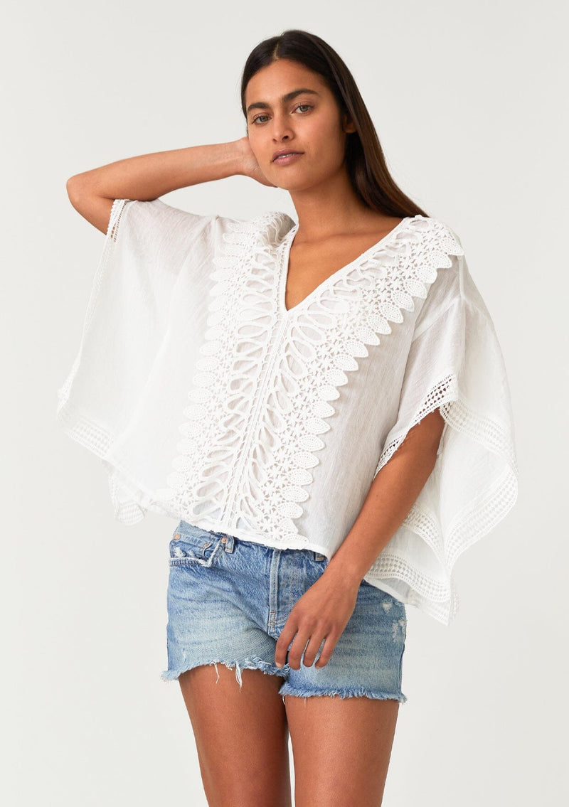[Color: Off White] A half body front facing image of a brunette model wearing a sheer white bohemian beach cover up top. With crochet lace trim, short sleeves, a v neckline, and a relaxed, boxy fit. Perfect for the beach or wearing over your swimsuit on your next vacation. 