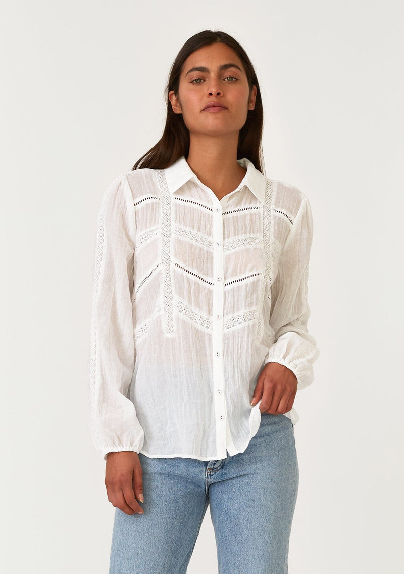 [Color: White] A front facing image of a brunette model wearing a sheer white bohemian shirt. With long sleeves, a collared neckline, a self covered button front, and lace trim. 
