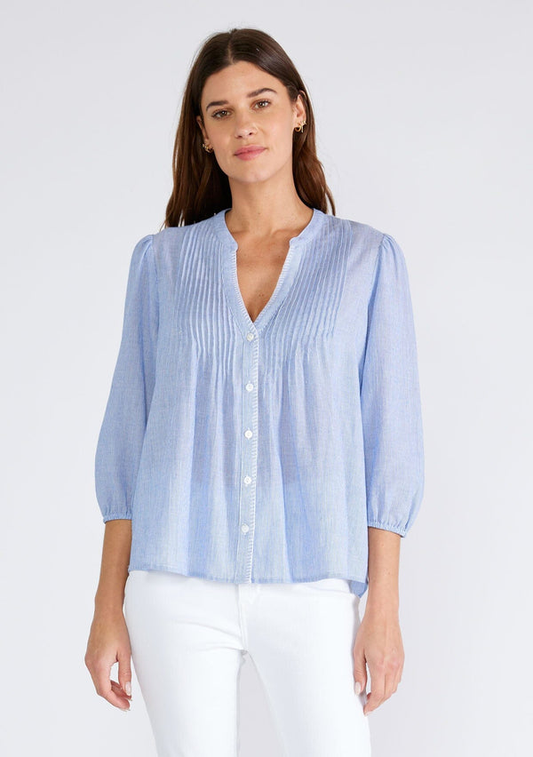 [Color: Chambray/Ivory] A front facing image of a brunette model wearing a classic cotton blouse in a blue and white pinstripe. With three quarter length sleeves, a split v neckline, a button front, pleated pintuck details, and contrasting blanket stitch details. The flowy fit is both comfortable and chic for spring. 