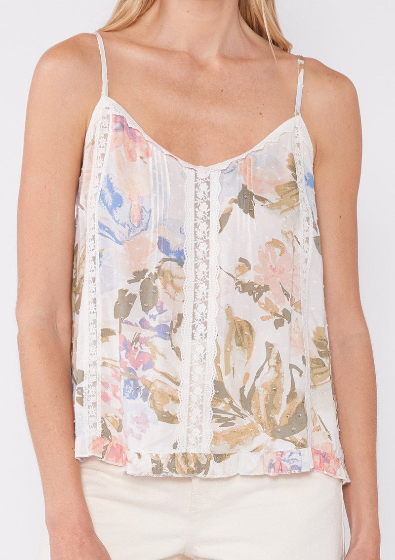 [Color: Off White/Periwinkle] A close up front facing image of a blonde model wearing a pretty bohemian camisole in an off white and periwinkle blue floral print. With lace trim, adjustable spaghetti straps, a v neckline, and a ruffled hemline. 