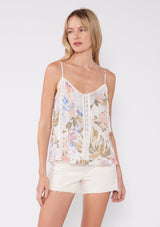 [Color: Off White/Periwinkle] A front facing image of a blonde model wearing a pretty bohemian camisole in an off white and periwinkle blue floral print. With lace trim, adjustable spaghetti straps, a v neckline, and a ruffled hemline. 