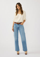 [Color: Cream] A front facing image of a brunette model wearing a cream bohemian embroidered blouse with a v-neckline and 3/4 length sleeves with ruffled cuffs. 