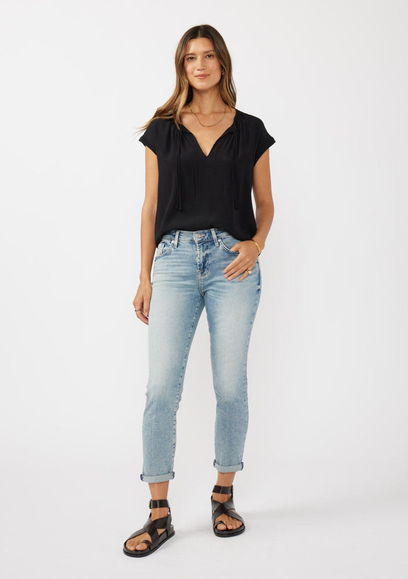 [Color: Black] A brunette model wearing a relaxed fit  black top. With self neck ties, ruched split v neckline, and short dolman sleeves. Styled with a cute vintage denim for a laid back look. 