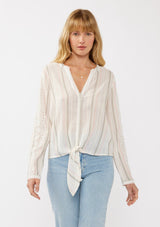 [Color: White/Coral] A front facing image of a blonde model wearing an off white yarn dye stripe top with embroidered eyelet details. This sheer  cotton top features a split v-neckline, long sleeves, button cuff closures, and a tie front hem detail. Perfect for vacation and resort styling. 