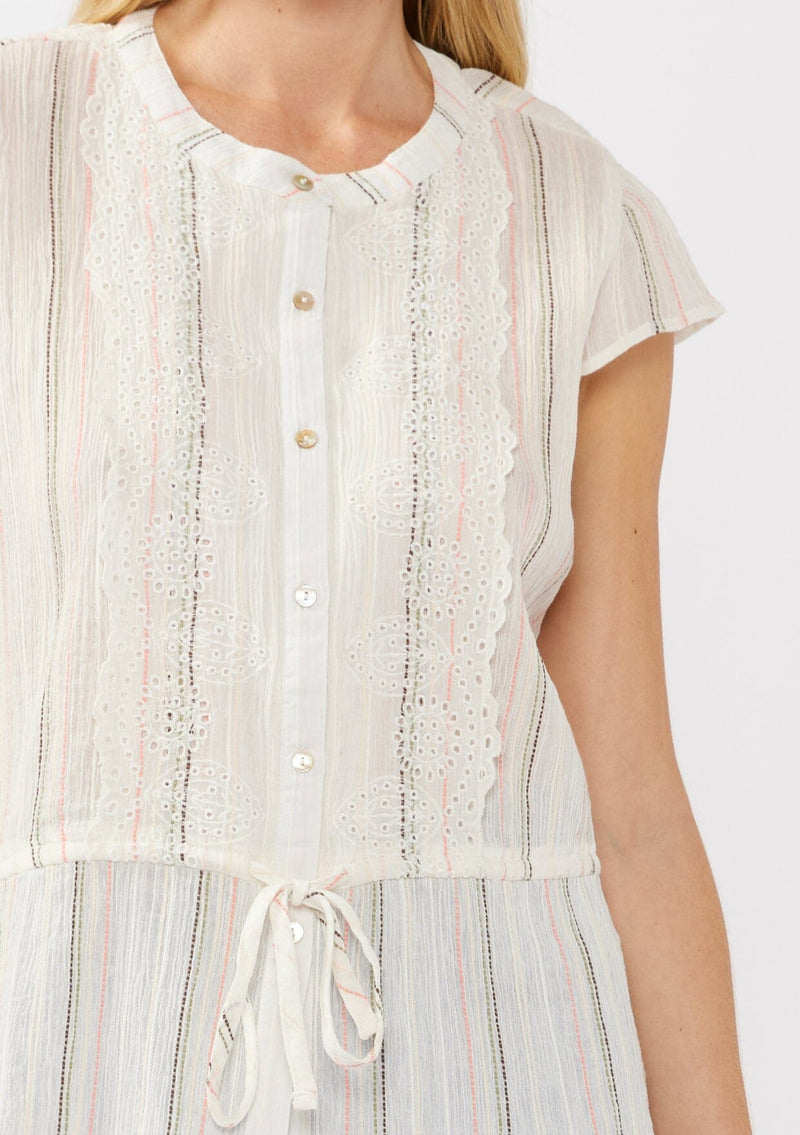 [Color: White/Coral] A detail image of a blonde model wearing an off white yarn dye stripe top with embroidered eyelet details. This sheer cotton top features a round neckline, button front, short sleeves, and a peplum waist with an adjustable drawstring. Perfect for casual outings and resort styling. 