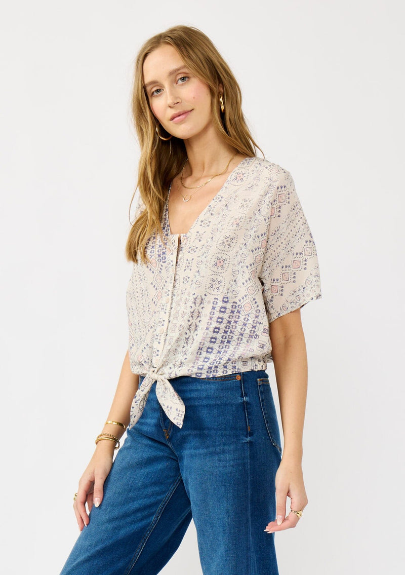 [Color: Oatmeal/Plum] A side facing image of a blonde model wearing a boho floral tie front top with short dolman sleeves, a v-neckline, and button front. 