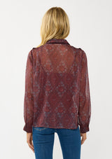 [Color: Wine/Rose] A back facing image of a blonde model wearing a floral diamond print chiffon blouse with metallic thread details. Featuring metallic thread details, a button front, and long sleeves with a tailored cuff. A special occasion top for the fall season. 