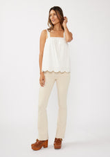 [Color: White] A front facing image of a blonde model wearing a white cotton eyelet tank top with adjustable straps and a scalloped hem. 