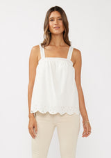 [Color: White] A front facing image of a blonde model wearing a white cotton eyelet tank top with adjustable straps and a scalloped hem. 
