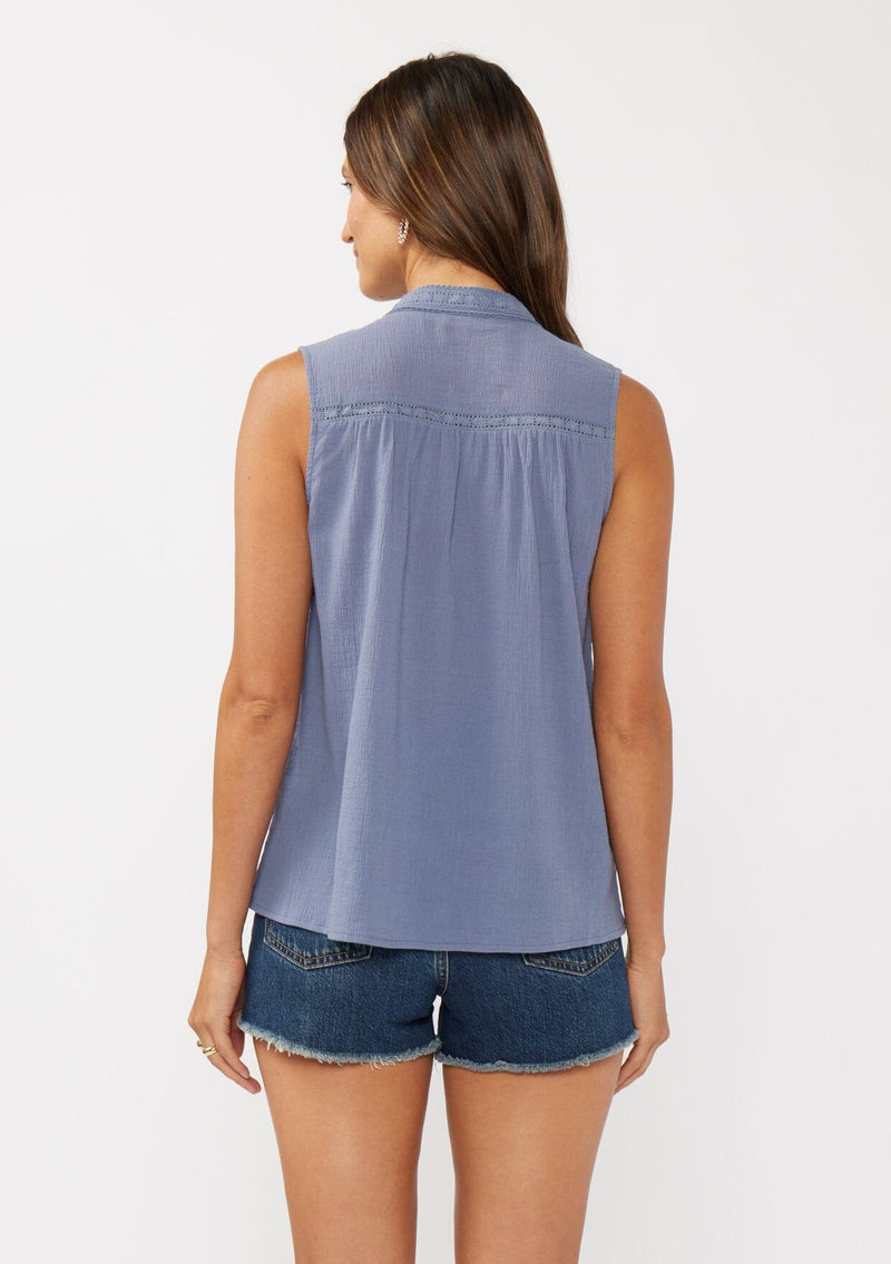 [Color: Denim Blue] A back facing image of a brunette model wearing a blue classic boho tank top with a button front, embroidered yoke, and lace trim accents. 