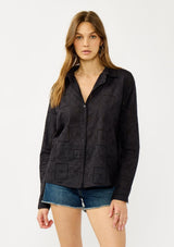 [Color: Graphite] A front facing image of a blonde model wearing a black eyelet shirt with a collared neckline, button front, and button cuff closure.