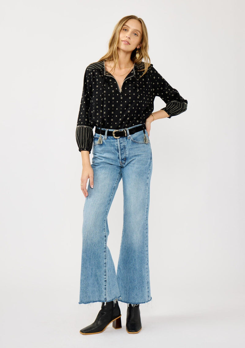 [Color: Black/Taupe] A front facing image of a blonde model wearing a black and taupe cotton jacquard blouse with a split v-neckline, tassel ties, long sleeves, and blanket stitch details. A fall bohemian top. 