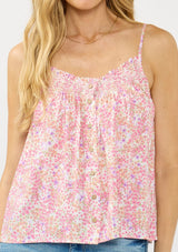 [Color: Natural/Dusty Rose] A detail image of a blonde model wearing a pink floral print camisole with a smocked neckline, button front, and adjustable spaghetti straps. 