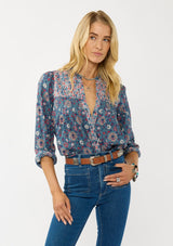 [Color: Teal] A front facing image of a blonde model wearing a blue floral blouse with a button front, quilted yoke detail, and long sleeves. A boho fall blouse for casual outings. 