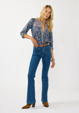 [Color: Teal] A front facing image of a blonde model wearing a blue floral blouse with a button front, quilted yoke detail, and long sleeves. A boho fall blouse for casual outings. 