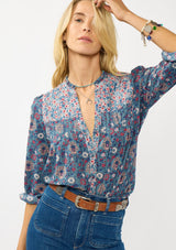 [Color: Teal] A front facing image of a blonde model wearing a blue floral blouse with a button front, quilted yoke detail, and long sleeves. A boho fall blouse for casual outings. 