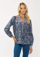 [Color: Teal] A front facing image of a blonde model wearing a blue floral blouse with a button front, quilted yoke detail, and long sleeves. A boho fall blouse for casual outings. 