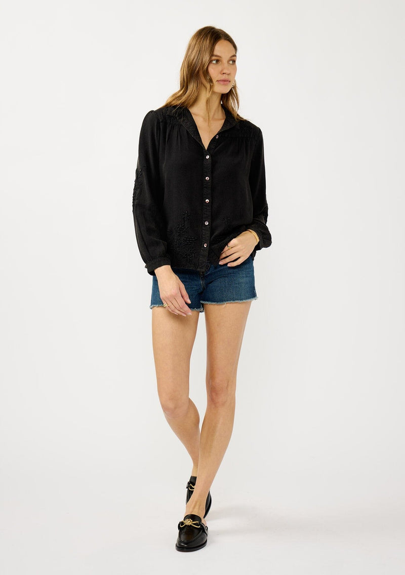 [Color: Black] A front facing image of a blonde model wearing a soft vintage wash black shirt with tonal embroidered details. Featuring a classic collar neckline, button front, and button cuff. 