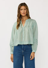 [Color: Dusty Sage] A front facing image of a brunette model wearing green lightweight blouse with pintuck accents, a button front, and split v-neckline. Airy and sheer for any warm weather occasion. 