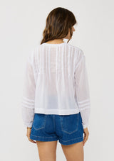 [Color: Black] A back facing image of a brunette model wearing white lightweight blouse with pintuck accents, a button front, and split v-neckline. Airy and sheer for any warm weather occasion. 