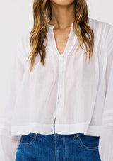 [Color: Black] A detail image of a brunette model wearing white lightweight blouse with pintuck accents, a button front, and split v-neckline. Airy and sheer for any warm weather occasion. 