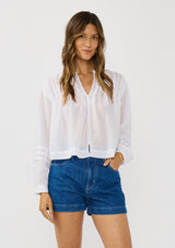 [Color: Black] A front facing image of a brunette model wearing white lightweight blouse with pintuck accents, a button front, and split v-neckline. Airy and sheer for any warm weather occasion. 