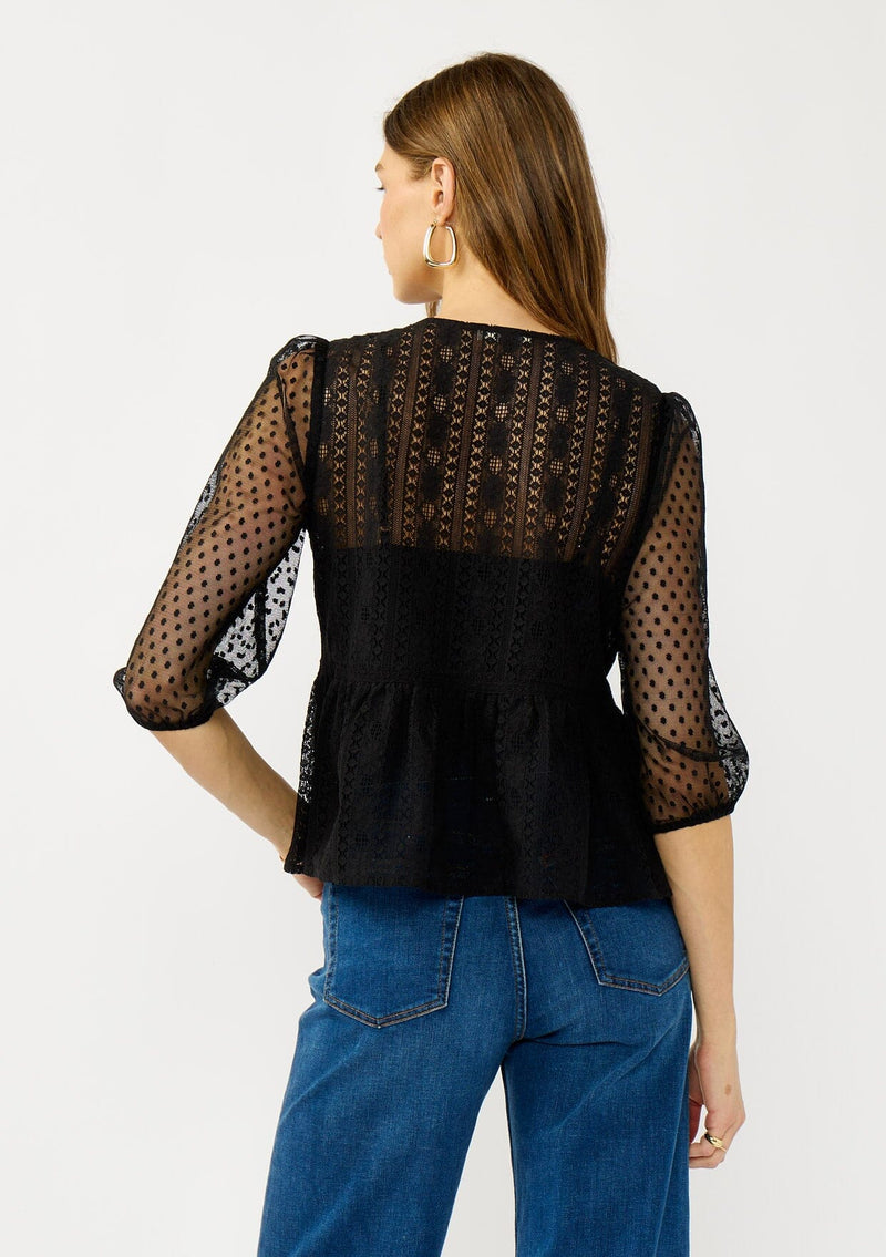 [Color: Black] A back facing image of a blonde model wearing a Victorian mixed lace top with 3/4 length sleeves, a split v-neckline, button front, and a subtle peplum-style silhouette. A versatile black fall lace top. 
