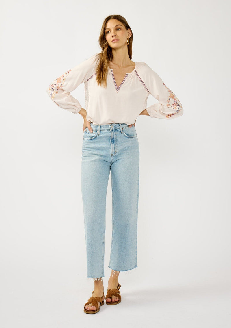 [Color: Pale Rose] A front facing image of a blonde model wearing a light pink blouse with floral embroidery, lace accents, and a flattering split v-neckline. Effortlessly boho and feminine for casual outings. 