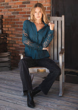 [Color: Teal] A front facing image of a blonde model wearing a striped jacquard teal shirt with lace cutouts, a button front, and collared neckline. A cool and polished blouse for the fall season. 