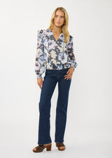 [Color: Grey/Navy] A front facing image of a blonde model wearing a grey and purple floral top with a split v-neckline, smocked waist and cuff, and a ruffle shoulder detail. A chic fall blouse for special occasions. 