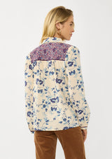 [Color: Cream/Plum] A back facing image of a blonde model wearing a purple and cream floral boho shirt with a classic collar neck and button front. A unique fall top for casual styling. 