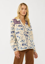 [Color: Cream/Plum] A front facing image of a blonde model wearing a purple and cream floral boho shirt with a classic collar neck and button front. A unique fall top for casual styling. 