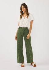 [Color: White] A front facing image of a brunette model wearing a white puff sleeve blouse with an eyelet inspired design and a split v-neckline with ties. 