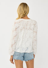 [Color: White] A back facing image of a blonde model wearing a white blouse with a clipped floral design, fuzzy texture, button front, and long sheer sleeves. An everyday warm weather style. 