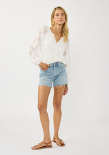 [Color: White] A front facing image of a blonde model wearing a white blouse with a clipped floral design, fuzzy texture, button front, and long sheer sleeves. An everyday warm weather style. 