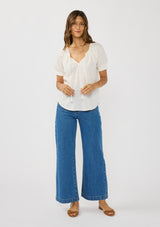 [Color: White] A front facing image of a brunette model wearing a lightweight white top with puff sleeves and a split neckline with tassel ties. 