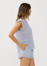 [Color: Blue/White] A side facing image of a brunette model wearing a blue and white striped top with rolled cap sleeves, a button front, and a mandarin collar.  