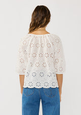 [Color: White] A back facing image of a brunette model wearing a white eyelet embroidered top with half sleeves and a button front. A classic spring top styled with denim. 