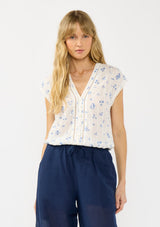 [Color: White/Blue] A front facing image of a blonde model wearing a white and blue floral top with a v neckline, short dolman sleeves, and an elastic hem at the back. 