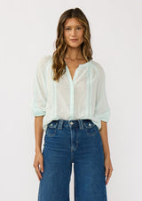 [Color: Mint] A front facing image of a brunette model wearing a sheer mint blouse with lace trims and a hidden button front.