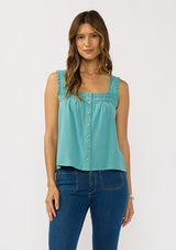 [Color: Teal] A front facing image of a brunette model wearing a bohemian teal tank top with a button front, square neckline, and wide straps with ruffle trims. 