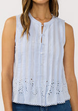 [Color: Blue] A detail image of brunette model wearing a light blue tank top with a button front, pintuck details, and an eyelet embroidered hem. 