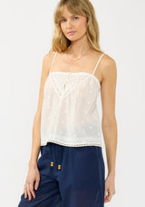 [Color: White] A front facing image of a blonde model wearing a white lace camisole with a square neckline, embroidered details, and adjustable spaghetti straps. 