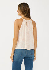 [Color: Shell/Cream] A back facing image of a brunette model wearing a light beige floral sleeveless top with a tie back detail.