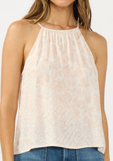 [Color: Shell/Cream] A detail image of a brunette model wearing a light beige floral sleeveless top with a tie back detail.