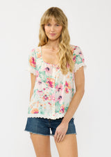 [Color: Ivory/Fuchsia] A front facing image of a blonde model wearing a spring floral top with an eyelet trim, a scoop neckline, and a button front. 